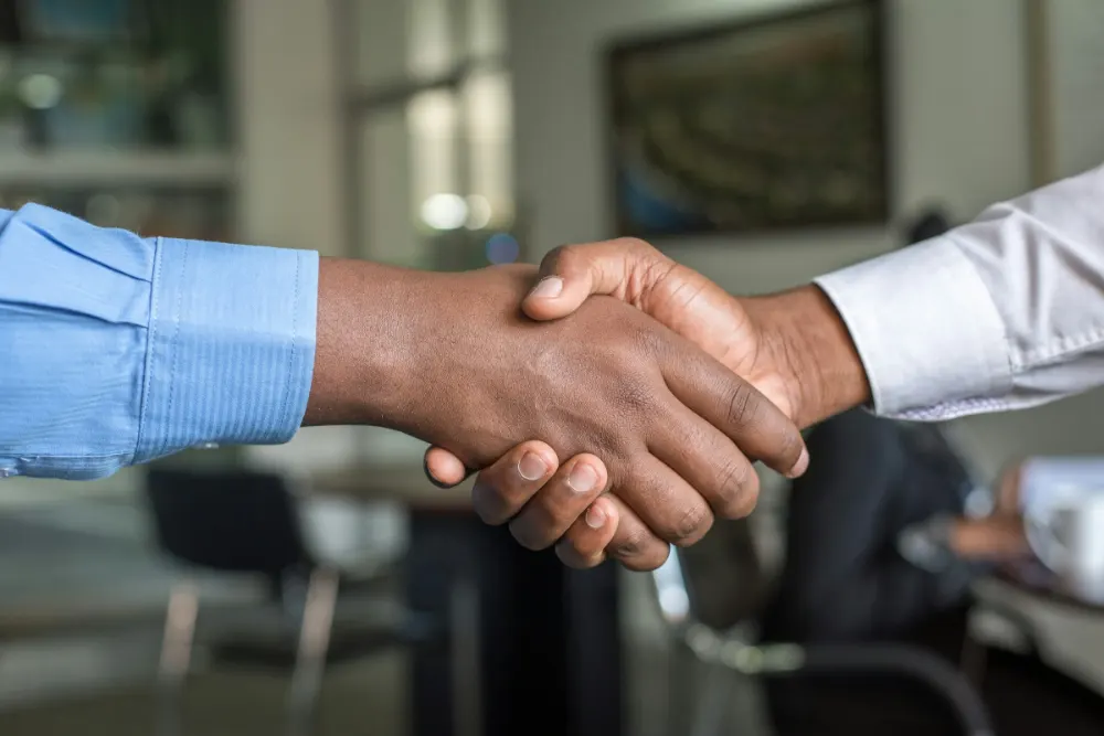 Two business partners shaking hands across a table in a Nairobi office